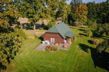 Büyüleyici ahşap ev yeşil bir çatı içerir ve canlı ağaçların arasına yerleşir. Rahatlamak ve doğanın tadını çıkarmak için mükemmel bir açık hava alanı sunar.