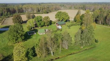 Hava perspektifi, bereketli ağaçlar ve kırsal yapılarla sakin bir kırsal alan yakalar, doğanın güzelliğini vurgular, manzarayı ortaya çıkarmak için kamera tavaları