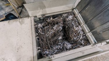 Parçalanmış kağıt ve metal artıklarıyla dolu atık yönetim konteynırı, sürdürülebilir atık imhası için geri dönüşüm çabaları ve endüstriyel süreçlerin vurgulanması