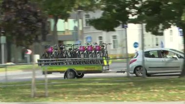 Parnu, Estonya - 11 Eylül 2025: Bisiklet römorku geçerken sırtında sırt çantası olan genç bir adam sokakta yürüyor, kamera aksiyonu takip ediyor