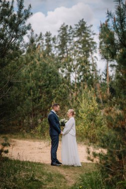 Yeşillik ve ağaçlarla çevrili güzel bir ormanda el ele tutuşan romantik çift, doğanın bağlılık ve sevgisinin özünü yakalıyorlar.