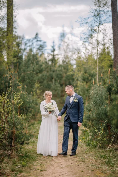 Zarif kıyafetler içindeki erkek ve kadın, yeşil ve ağaçlarla çevrili güzel bir ormanda el ele tutuşuyorlar. Doğadaki sevgi ve birliği simgeliyorlar.