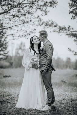 Düğün kıyafetli çift, doğal güzellik ve sükunet arasında sevgi ve bağlantı gösteren sakin bir ortamda hassas bir anın tadını çıkarıyor.