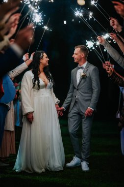 Çift, misafirler tarafından oluşturulan bir maytap tünelinde el ele yürüyor. Büyülü bir atmosferle çevrili. Düğünlerini neşe ve heyecanla kutluyorlar.