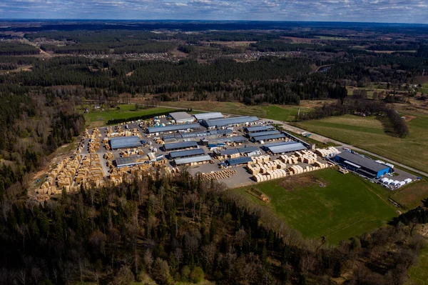 Valmiera, Letonya - 01 Mayıs 2021: Yeşil ormanlar ve kırsal alanda açık alanlarla çevrili, yukarıdan ele geçirilen büyük kereste fabrikası