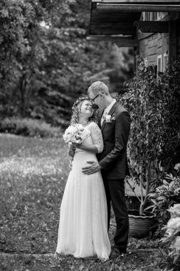 Düğün kıyafetli çift, canlı bir bahçede, doğa ile çevrili, birbirlerine olan sevgilerini ve bağlılıklarını kutlayan hassas bir anı paylaşırlar.