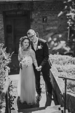 Resmi nikah kılığındaki çift basamaklarda duruyor, yemyeşil ile çevrili, doğal ışıkla dolu sakin bir ortamda sevgi ve neşe sergiliyorlar.