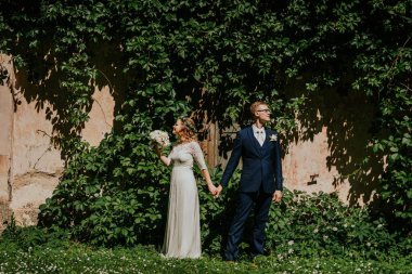 Zarif gelin ve damat, canlı yeşilliklerle çevrili, doğal güzelliklerle dolu güzel bir açık hava ortamında aşklarını ve neşelerini sergiliyorlar.