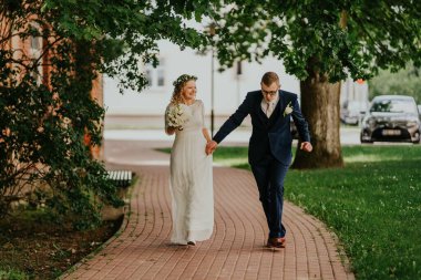 Mutlu çift, neşeli yeşilliklerle çevrili büyüleyici bir yolda birlikte dolaşır. Düğün günlerinin ruhunu neşe ve romantizmle yakalar.