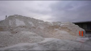 Endüstriyel ayar büyük bir sentetik alçı yığını içeriyor, pürüzsüz bir kamera zoom ile, bulutlu bir arkaplana karşı onun dokusunu ve ölçeğini vurguluyor