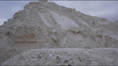 Endüstriyel ayar sentetik alçıtaşı üretimini vurguluyor, kademeli kamera zoom ile sahne dokularını ve malzeme dinamiklerini ortaya çıkarıyor