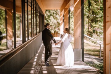 Nişanlı çiftler güzel bir yolda, ağaçların ve modern binaların arasından süzülen doğal ışıkla birlikte bir neşe ve yakınlık anı yakalıyorlar.