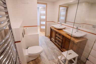 Çağdaş banyo tasarımı ahşap kibir üzerine çift lavabo, parlak tuvalet, ısıtılmış havlu askı, ferah ve modern estetiği vurgulayan parlak bir çevrede