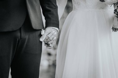 Düğün kıyafetleri içinde el ele tutuşan çift, güzel bir açık hava ortamı ile çevrili, sevgi ve birliğin özünü kalpten bir anda yakalıyorlar.