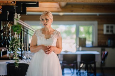 Beyaz gelinlik içinde zarif bir gelin çiçek süslemeleri ve hafif ışıklandırmalarla süslenmiş, sevgi ve kutlamanın ruhunu somutlaştıran bir mekanda duruyor.