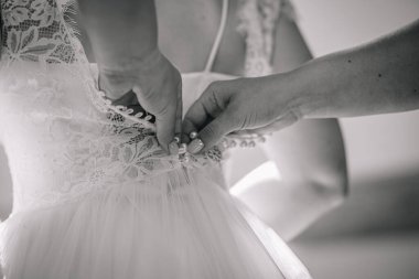 Bir gelinliğin yakın plan çekimi, hassas dantel ve tül dokuları vurguluyor, düğün hazırlıkları sırasında aşkı ve beklentiyi sembolize ediyor