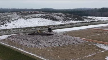 Cesis, Letonya - 21 Kasım 2025: Havadan alınan görüntüler çöp sahasındaki inşaat makinelerini, karlı araziyi ve enkazı yakalamak için kamera tavalarını gösteriyor