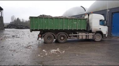 Cesis, Letonya - 21 Kasım 2025: Çöp kamyonu geri dönüşüm tesisine çöp boşaltıyor, kamera tavaları yakınlardaki büyük çöp yığınını gösteriyor