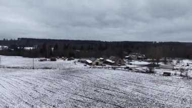 Cesis, Letonya - 21 Kasım 2025: Hava görüntüleri karla kaplı tarlaları ve çiftlik evlerini yakalıyor, kamera kırsal manzarayı ve ambiyansı düzgün bir şekilde gösteriyor