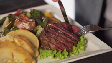 Dilimlenmiş biftek, renkli sebzeler ve mezeler sergilenen gurme yemeğin yakın çekim görüntüsü, kamera yiyeceklerin dokularını ve sunumunu ön plana çıkarırken,