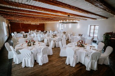Beyaz çarşaflı ve çiçeklerle süslenmiş yuvarlak masaların bulunduğu güzel bir ziyafet salonu. Yumuşak peri ışıklarıyla aydınlatılmış. Kutlamalar ve toplantılar için mükemmel.