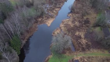 Hava perspektifi yemyeşil ve canlı dokularla çevrili dolambaçlı bir nehri yakalar ve giderek genişleyen doğal manzarayı ortaya çıkarmak için uzaklaşır.
