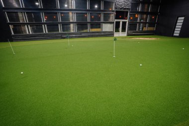 Kapalı alanda golf oynayarak yeşil özellikler suni çim, birkaç delik ve şık ortam aydınlatması golf pratiği için çağdaş bir alan sağlıyor.