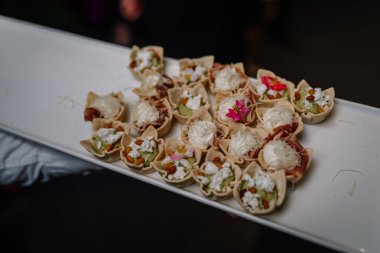 Beyaz bir tabakta sergilenen nefis gurme aperatifler peynir, otlar ve renkli yenilebilir çiçeklerle dolu hamur kabukları üst düzey etkinlikler için mükemmeldir.
