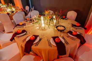 Çiçekler, mumlar ve dekoratif malzemelerle güzelce düzenlenmiş şenlikli yemek masası, özel bir kutlama ya da toplanma ortamı yaratıyor.