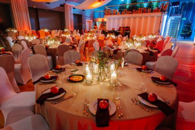 Yuvarlak masalar, beyaz masa örtüleri, mumlar ve dekoratif aksanlar ile zarif bir şekilde ayarlanmış. Şenlikli bir kutlama ya da özel bir etkinlik için sıcak ve davetkar bir ortam yaratıyorlar.