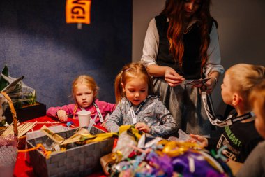 Riga, Letonya - 24 Ekim 2025 Cadılar Bayramı partisi. Çocuklar, malzeme ve dekorasyonlarla dolu canlı sınıflarda hocalarıyla birlikte sanat ve zanaata katılıyorlar.