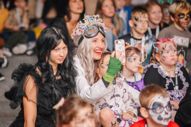 Riga, Letonya - 24 Ekim 2025 Cadılar Bayramı partisi. Çocuklar ve yetişkinler Cadılar Bayramı 'nı kostümler, boyalı yüzler ve neşeli ifadelerle kutluyorlar.