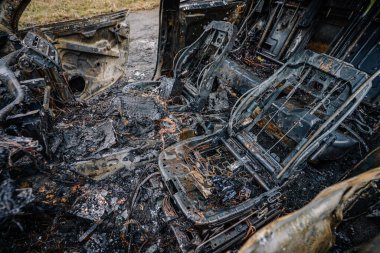 Yanmış koltuklar ve hasarlı parçalarla dolu yanmış bir araç. Terk edilmiş bir yerde meydana gelen yangının yıkımını gösteriyor.