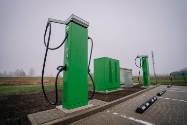 Elektrikli araç şarj istasyonları modern tasarım ve çevre dostu teknolojinin sergilendiği, sürdürülebilirlik ve yeniliğin vurgulandığı çağdaş bir otoparka yerleştirilmiştir.