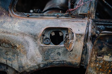 Terk edilmiş bir aracın yıpranmış yakıt kapısının yakın çekimi paslı ve karmaşık dokuları ortaya çıkarıyor, zamanın etkilerini vurguluyor ve otomotiv yüzeylerini ihmal ediyor.