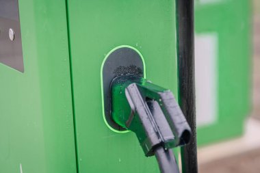 Elektrikli araç şarj istasyonu, sürdürülebilir enerji seçenekleri ve yenilikçi teknolojiyi ön plana çıkaran şarj konnektörlü yeşil bir tasarıma sahiptir.