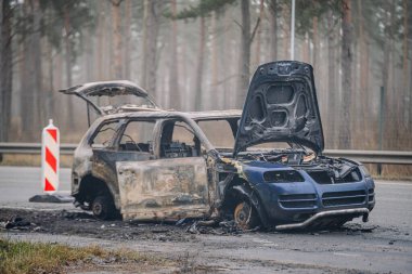 Yol kenarında terk edilmiş, kaputu açık, ağaçlar ve sisle çevrili, hasar ve yıkım gösteren terk edilmiş bir araç kasvetli bir atmosfer yaratıyor.