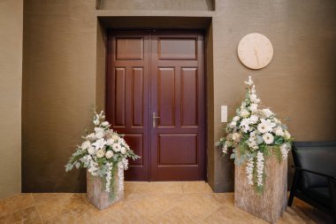 Güzel giriş gösterileri çiçek aranjmanlarıyla çevrili çift ahşap kapılar, çağdaş iç tasarımın cezbedici atmosferini artırıyor.