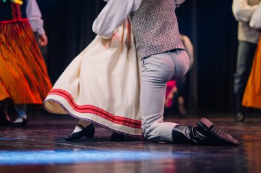 Letonyalı halk dansçısı sahnede renkli kostümleri ve dinamik hareketleri vurguluyor ve enerjik bir kültürel ifade atmosferi yaratıyor.