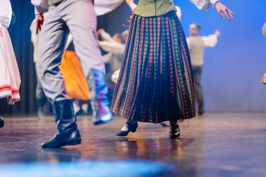 Geleneksel Letonyalı halk dansçıları canlı kostümlerini ve ritmik hareketlerini dans yoluyla kültürel mirası ve toplum ruhunu kutlayarak sahnede sergiliyorlar.