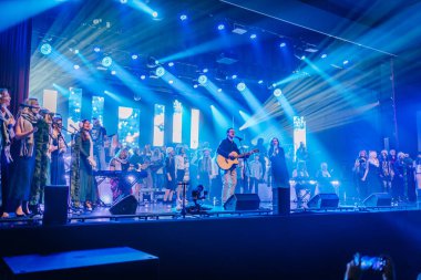 Valmiera, Letonya - 29 Aralık 2025: Yamaha. Sahnede büyük bir koro sahne alıyor. Arka planda müzik aletleri çalan müzisyenler var.