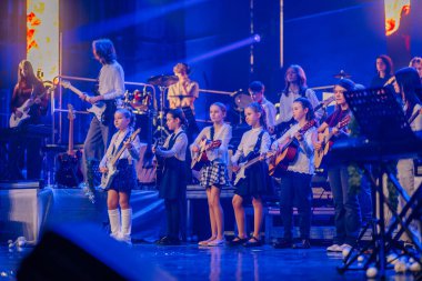 Valmiera, Letonya - 29 Aralık 2025: Yamaha. Sahnede gitar ve davul çalan bir grup genç müzisyen, canlı bir konser atmosferinde yetenek ve enerji sergiliyorlar.