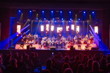 Valmiera, Letonya - 29 Aralık 2025: Yamaha. Çeşitli bir grup müzisyen sahnede canlı performans sergiliyor, enerjik bir atmosferde gitarlar ve canlı ışıklandırma efektleri sergiliyorlar.