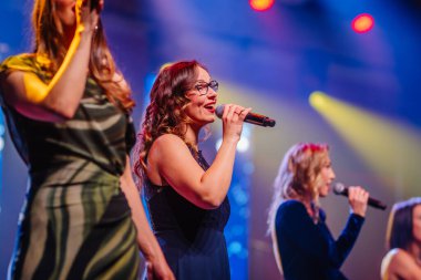 Valmiera, Letonya - 29 Aralık 2025: Yamaha. Sahnede canlı ışıklarla çevrelenmiş, enerjik bir atmosfer yaratan kadınlar.