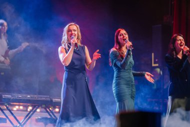 Valmiera, Letonya - 29 Aralık 2025: Yamaha. Kadın vokalistler, dinamik performansları ve renkli ışıklandırma efektleriyle seyircileri büyülüyor.