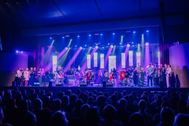 Valmiera, Letonya - 29 Aralık 2025: Yamaha. Sahnede çeşitli müzisyenlerin olduğu dinamik canlı konser seyirciler için enerjik bir ortam yaratıyor.