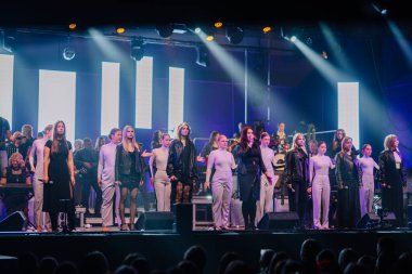 Valmiera, Letonya - 29 Aralık 2025: Yamaha. Kadın şarkıcılar sahnede canlı ışıklandırma ve şık kıyafetlerle yeteneklerini sergiliyorlar.