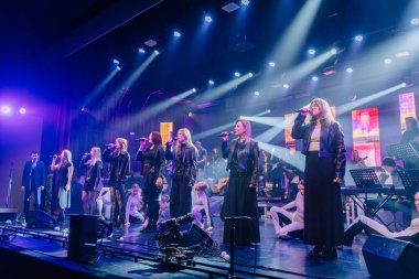 Valmiera, Letonya - 29 Aralık 2025: Yamaha. Şarkıcılar renkli ışıklarla sahne alıyor ve arka planda enstrümanlar çalıyorlar.