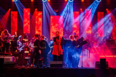 Valmiera, Letonya - 29 Aralık 2025: Yamaha. Şarkıcı sahnedeki seyirciyi canlı müzik grubu, canlı ışıklar ve performansı artıran renkli fon ile büyülüyor.