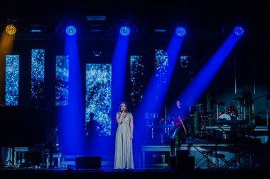 Valmiera, Letonya - 29 Aralık 2025: Yamaha. Kadın vokalist, canlı ışıklandırma ve enerjik bir atmosfer yaratan müzisyenlerle sahnede seyircileri cezbediyor.